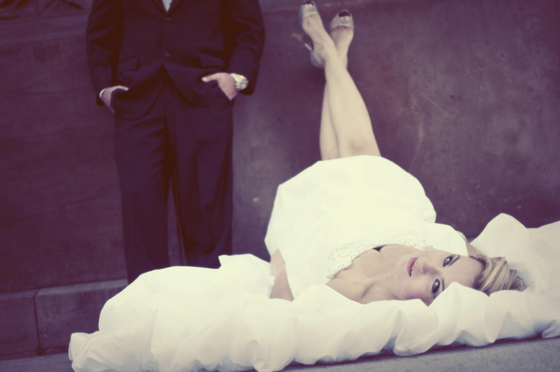 Bride is laying on the road, groom is looking at the bride
